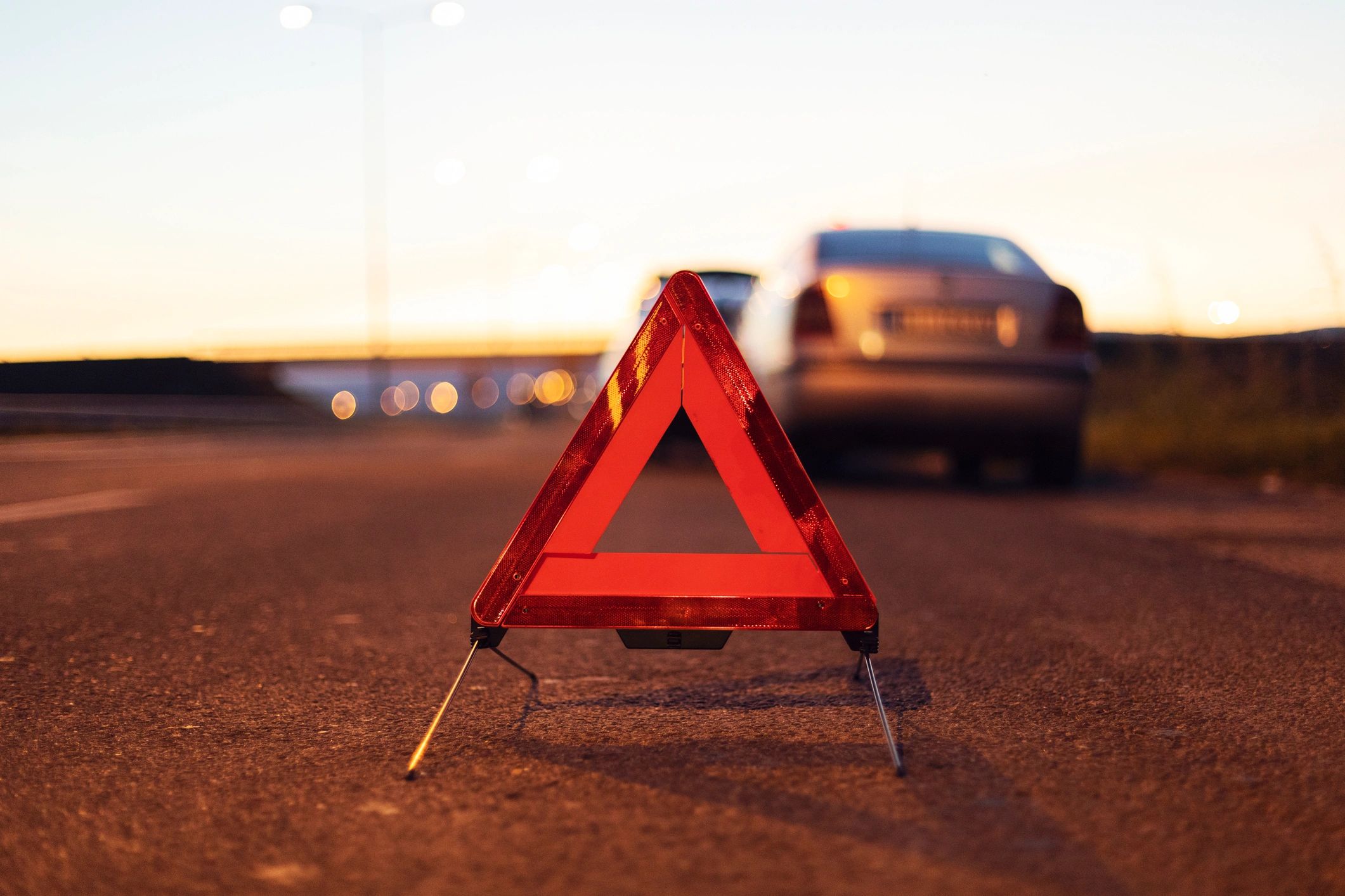 Roadside assistance warning triangle near a broken down car
