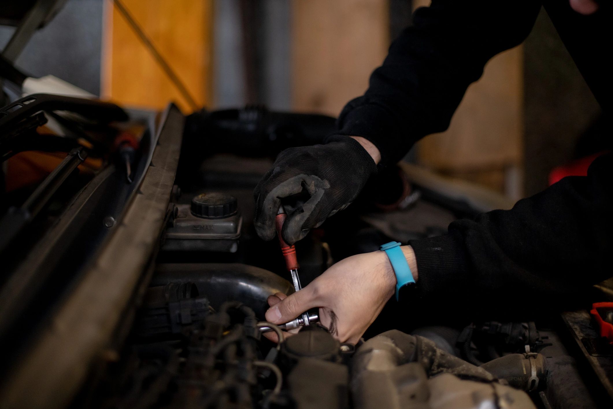 Mechanic performing repair work under a car hood