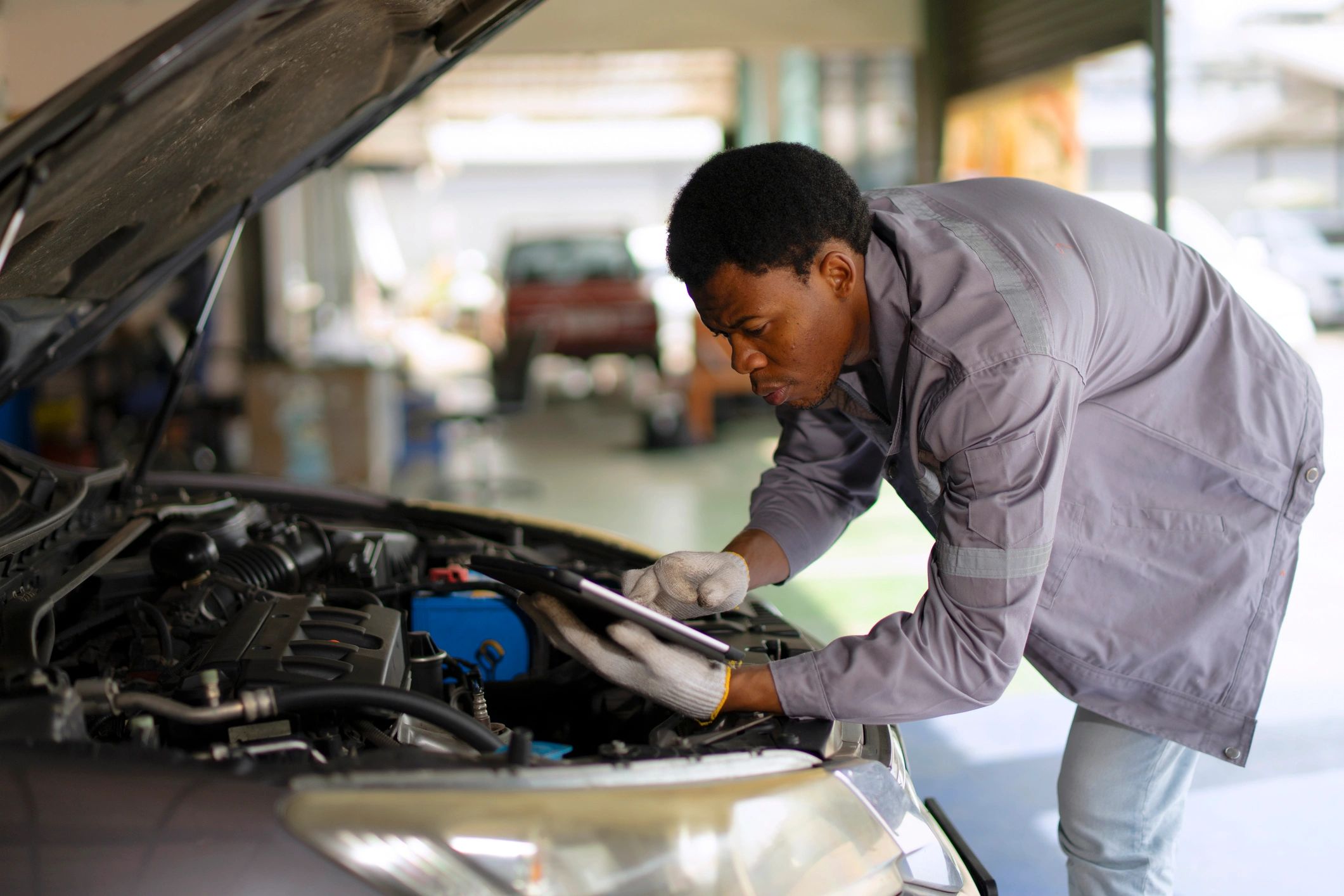 Mechanic inspecting a car engine in a service workshop